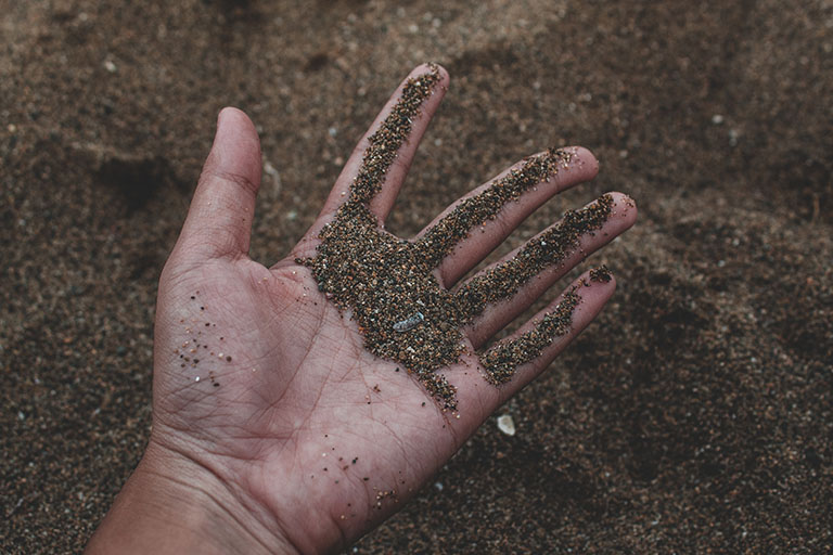 Hand in sandy soil